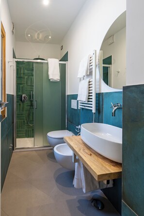 A modern bathroom with a glass shower enclosure, a white toilet, and a large white sink with a wooden countertop.