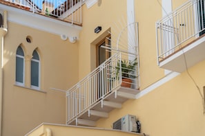Un edificio con fachada amarilla, barandillas blancas y una ventana con arco decorativo.