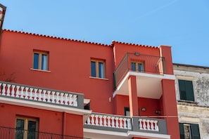 A red building with a balcony and a window. - Residence Palazzo Verderame (Amalfi)
