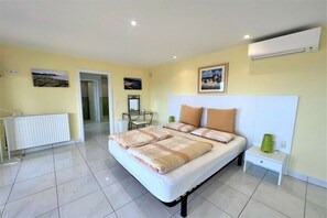 A bedroom with a bed, bedside tables, a radiator, and artwork on the walls. - Holiday home in Roses with swimming pool (Roses)