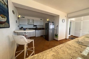 A compact kitchen with a refrigerator, a sink, and a dining area with chairs. - Holiday home in Roses with swimming pool (Roses)
