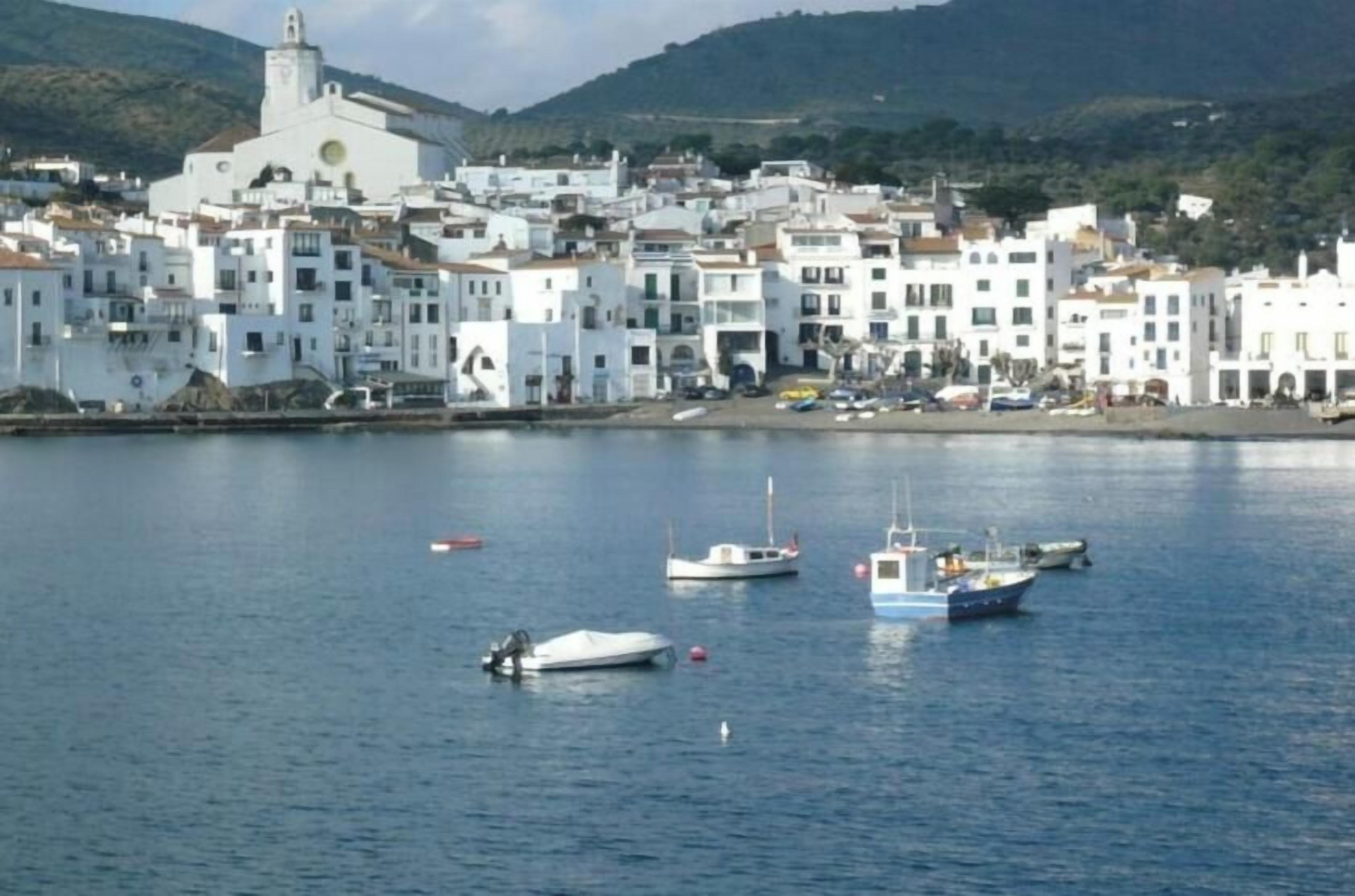 A coastal town with white buildings, a church, and boats on the water.