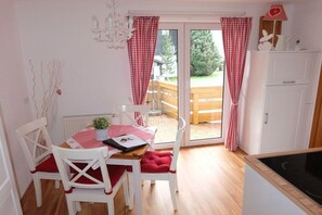 A dining area with a table, chairs, and a view through a glass door to an outdoor deck. - Allgäu Hearts 1 and 2 (Kornau\/Oberstdorf)