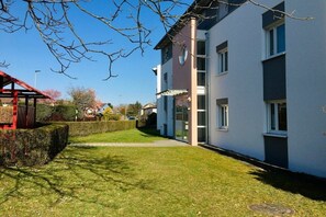 Um edifício moderno com telhado plano, grandes janelas e um gramado bem cuidado.