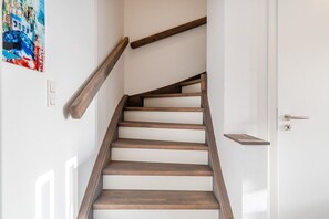 Eine Holztreppe mit einer weißen Tür am Oberende.