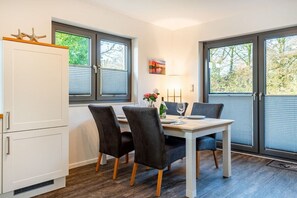 Spiseplads med bord, stole og et hvidt skab.