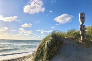 A coastal scene with a sandy beach, grassy dunes, and a clear sky. - Holiday home in Hörnum with swimming pool (Hörnum)