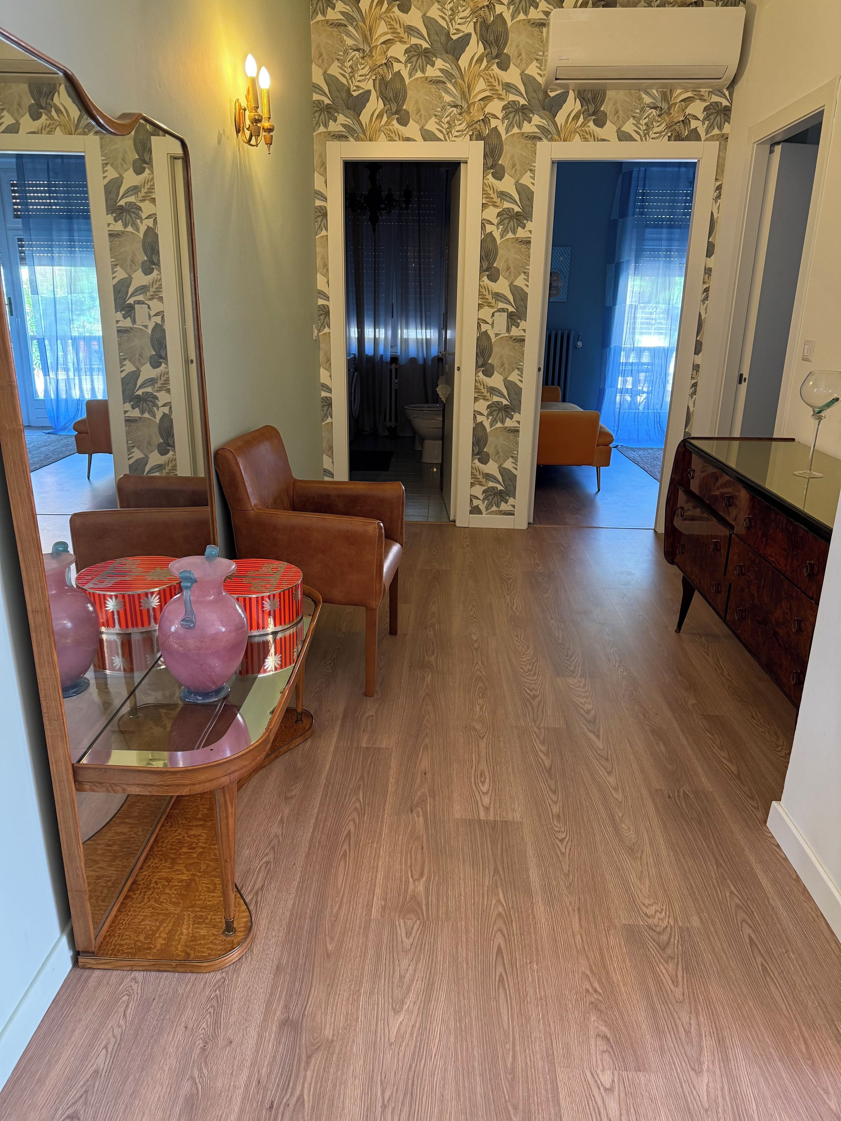 Un salon doté d’un parquet, d’une table basse en verre, de fauteuils en cuir marron et d’un meuble en bois sur lequel est posé un verre à vin.