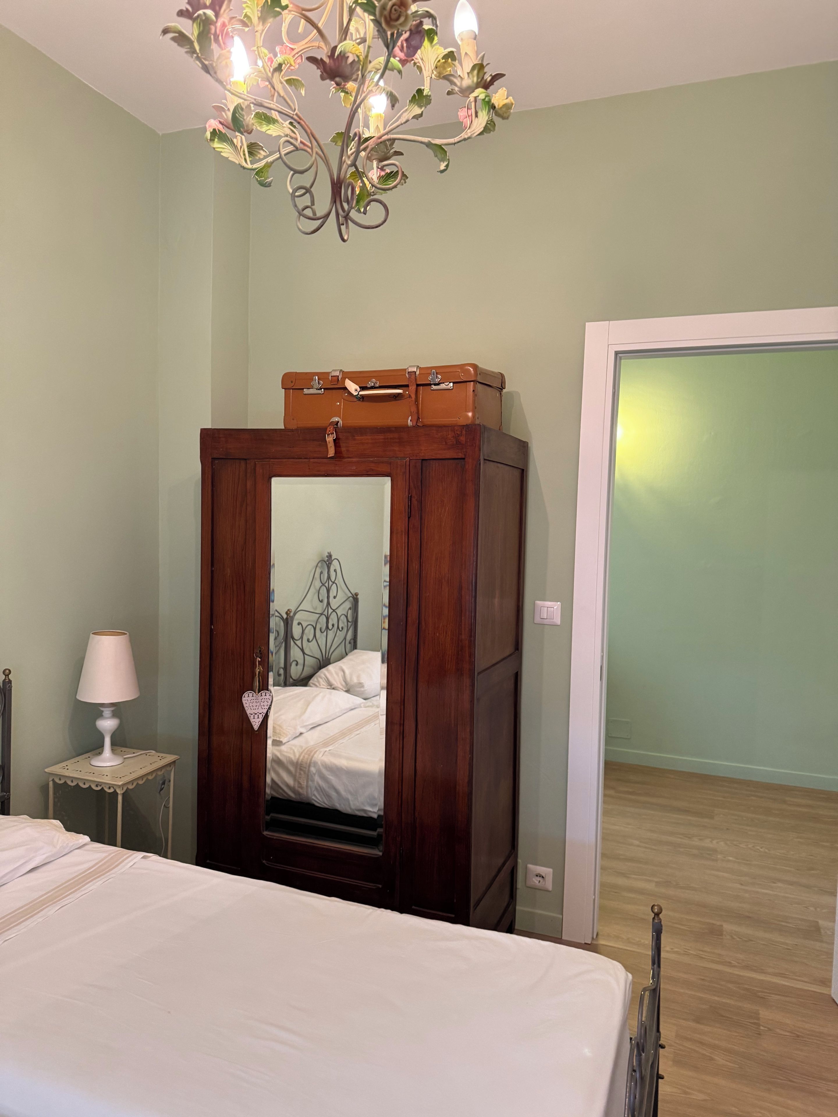 Une chambre à coucher avec un lit, une armoire en bois, une table de chevet avec une lampe et un lustre.