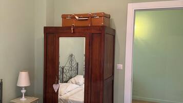 Une chambre à coucher avec un lit, une armoire en bois, une table de chevet avec une lampe et un lustre.