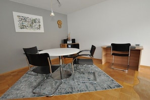 Un comedor moderno con una mesa redonda, cuatro sillas, un tapete, un reloj y un mueble bajo.