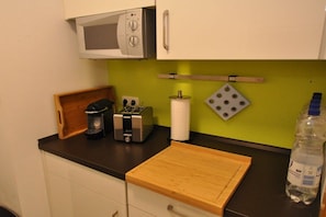 A kitchen with a microwave, toaster, and a wooden cutting board on the counter. - Holiday apartment with 1 bedroom (Schwangau)