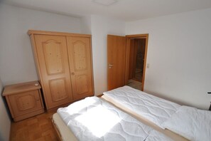 Un dormitorio con cama, armario de madera y puerta que da a otra habitación.