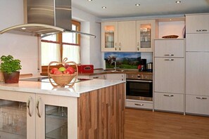 A modern kitchen with wooden cabinetry, a central island, and stainless steel appliances. - Wildbach - Herb Family (Rettenberg)