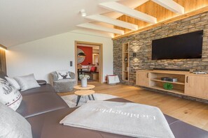 Una sala de estar moderna con una pared de acento de piedra, un televisor de pantalla plana y un rincón de descanso acogedor.