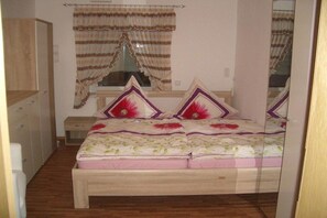 A bedroom with a bed, a nightstand, a wardrobe, and curtains. - All Inclusive Card Holiday Apartment 1-Heigl (Viechtach)