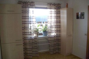 A room with a window, curtains, a radiator, and a potted plant. - All Inclusive Card Holiday Apartment 1-Heigl (Viechtach)