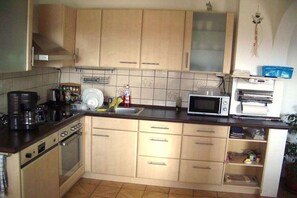A kitchen with wooden cabinets, a microwave, a coffee maker, and a toaster. - All Inclusive Card Holiday Apartment 1-Heigl (Viechtach)