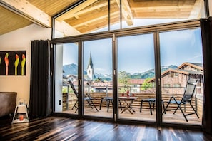 A room with a large sliding glass door leading to an outdoor deck with chairs and tables. - Holiday apartment with 2 bedrooms (Oberstdorf)
