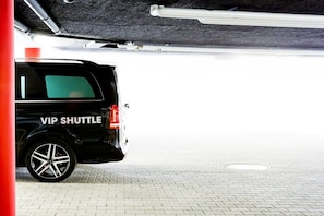 A black SUV labeled 'VIP SHUTTLE' parked in a covered parking area with a tiled floor. - Holiday apartment with 2 bedrooms (Oberstdorf)