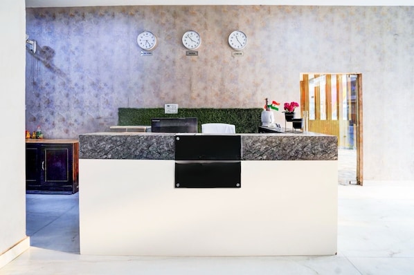 A reception desk with clocks indicating time in New York, India, and London.