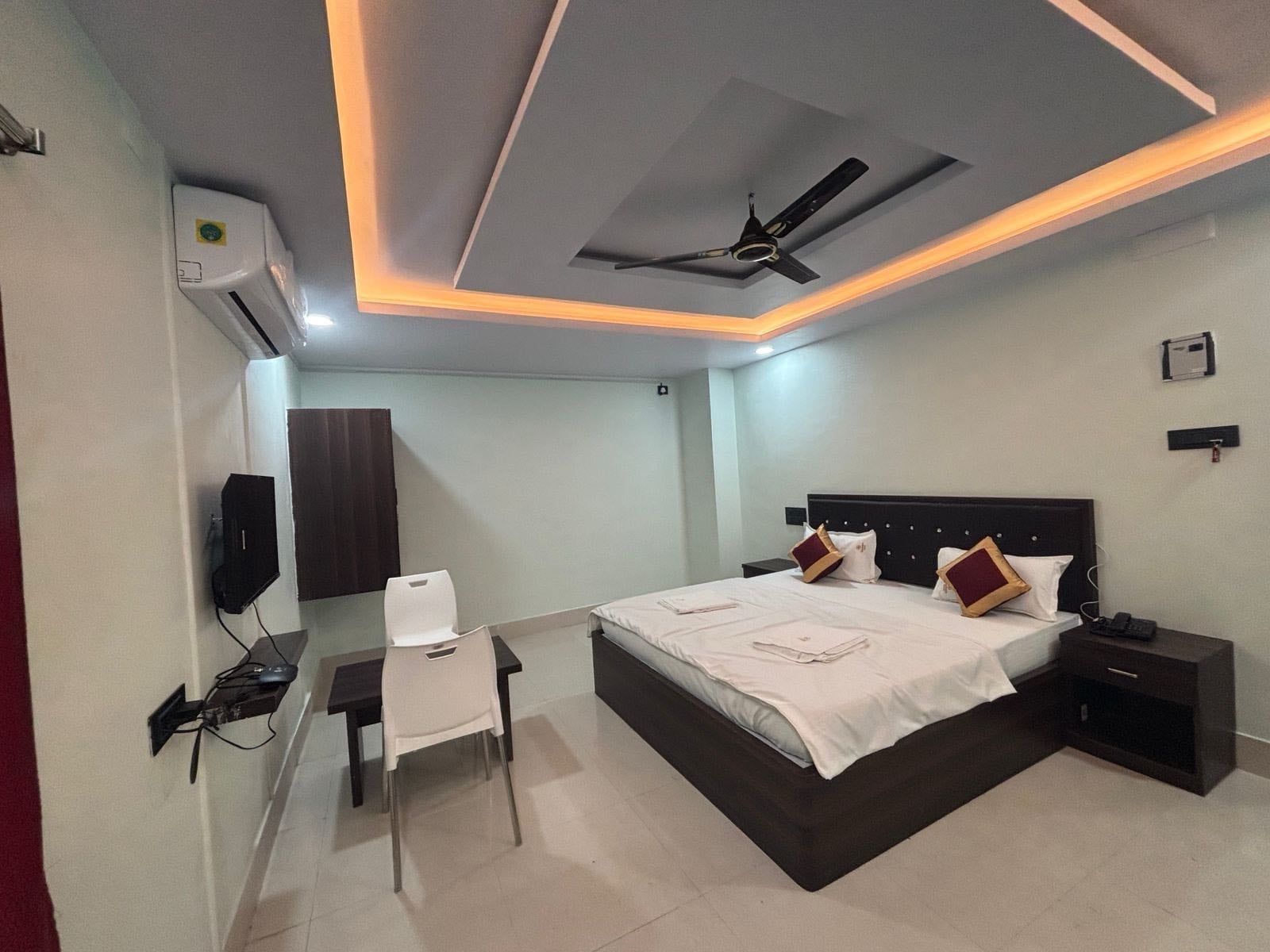 Une chambre d’hôtel équipée d’un lit, d’une table de chevet, d’une chaise, d’un ventilateur de plafond et d’un appareil de climatisation.