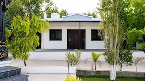 A modern two-story building with a flat roof, a front entrance with a dark door, and a small porch area.