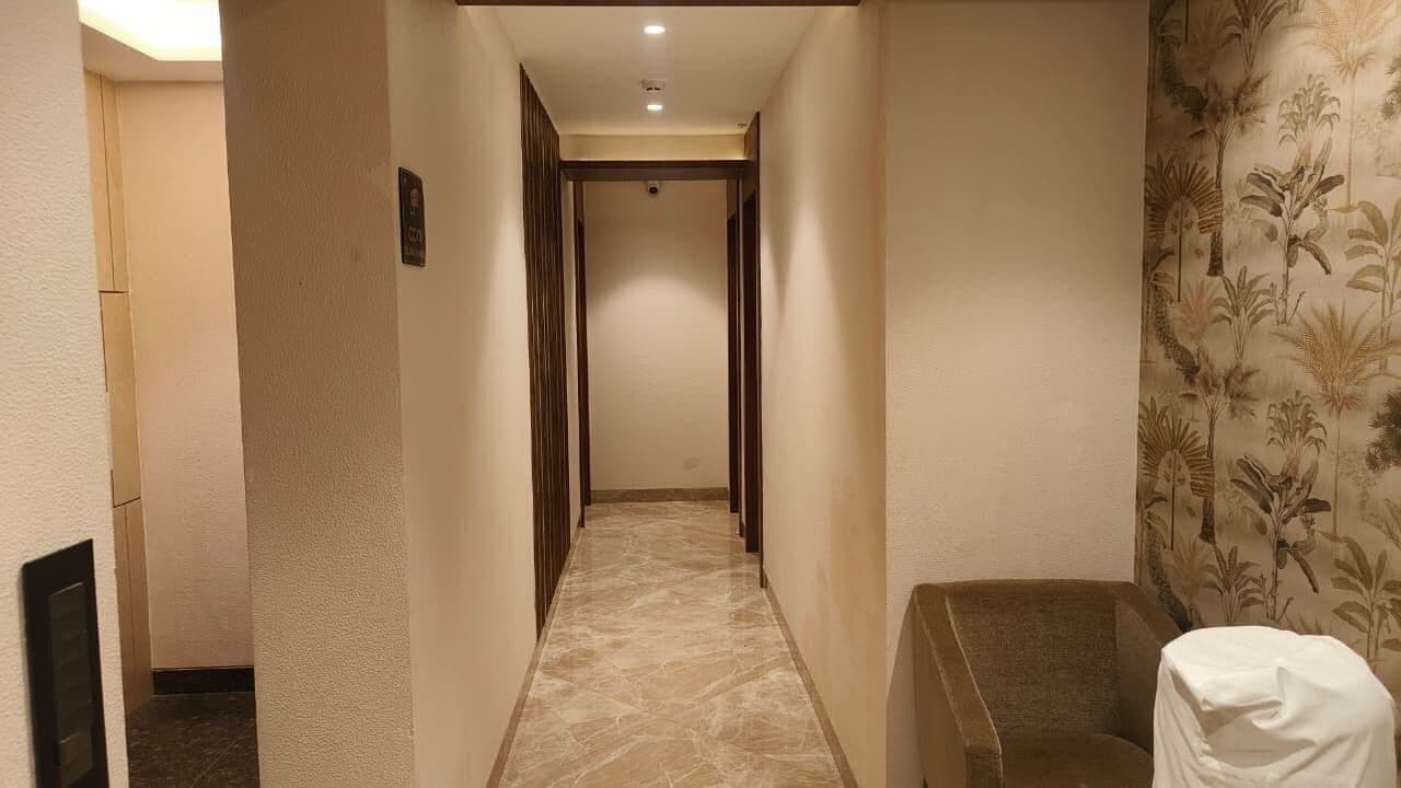 A hotel hallway with a marble floor, wooden doors, and a patterned wall.
