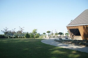 A grassy outdoor area with a building featuring a sloped roof and a wooden facade. - Holiday apartment with 2 bedrooms (Wasserburg)