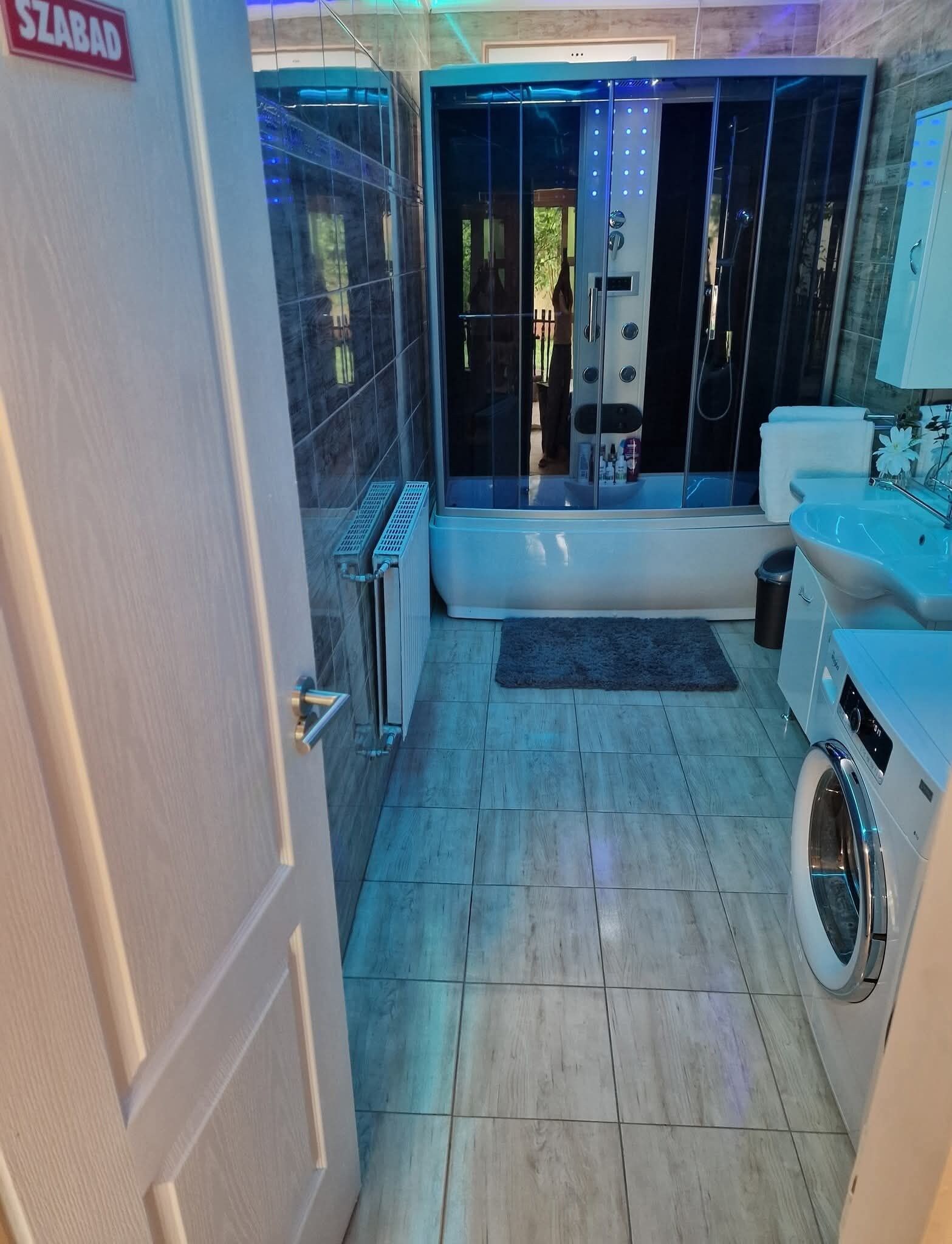 Ein Badezimmer mit einer Badewanne, einer Waschmaschine und einer Duschkabine aus Glas.