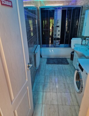 Ein Badezimmer mit einer Badewanne, einer Waschmaschine und einer Duschkabine aus Glas.