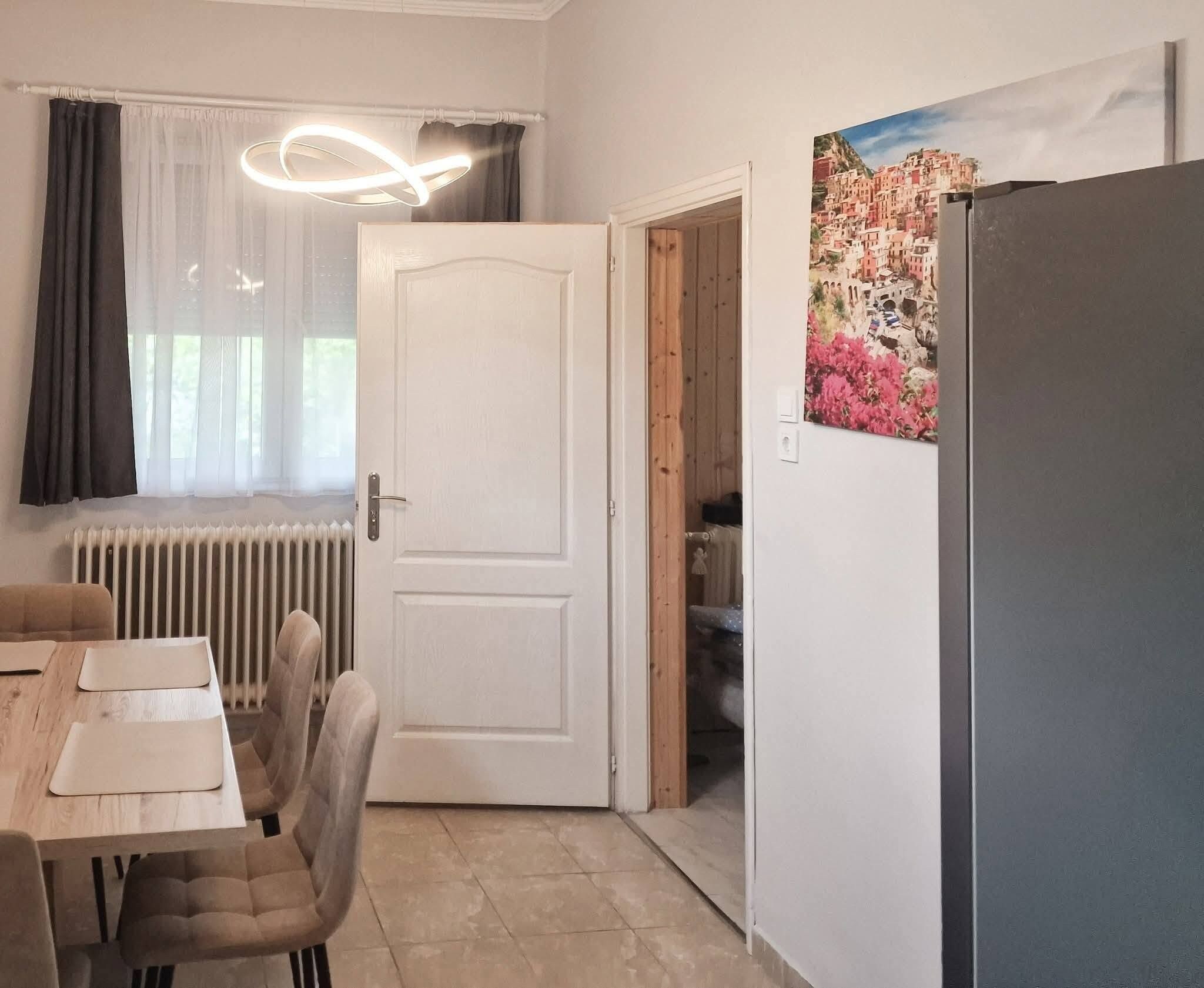 Ein Zimmer mit Esstisch, Stühlen, einem Heizkörper, einer Tür und einem Wandbild.