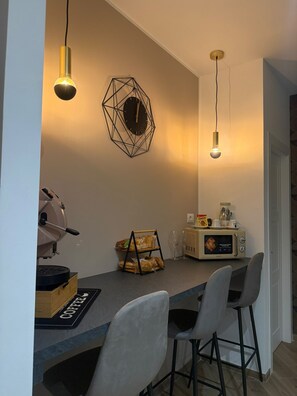 Eine moderne Küche mit Essbereich, darunter eine Kaffeemaschine, eine Mikrowelle und ein Brötchenkorb.