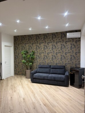 Ein modernes Wohnzimmer mit einem dunklen Sofa, einer Topfpflanze und einer Wand mit Muster.