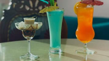 Tres bebidas sobre una mesa, con una silla decorativa al fondo.