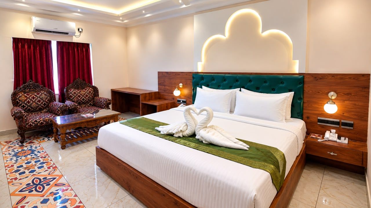 Habitación de hotel con una cama grande, una mesita de noche de madera, una silla, un escritorio y un alfombra estampado.
