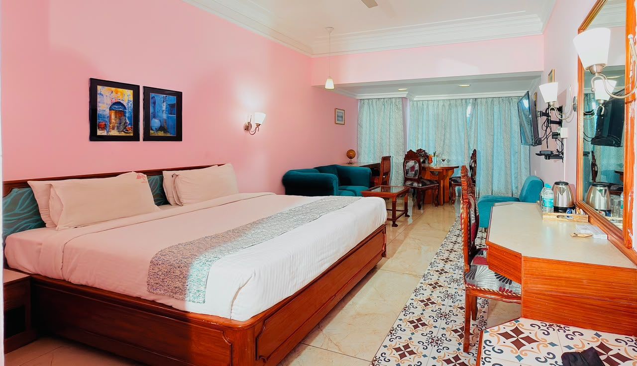 Una habitación de hotel con una cama grande, un escritorio, una silla, un televisor y un espejo.