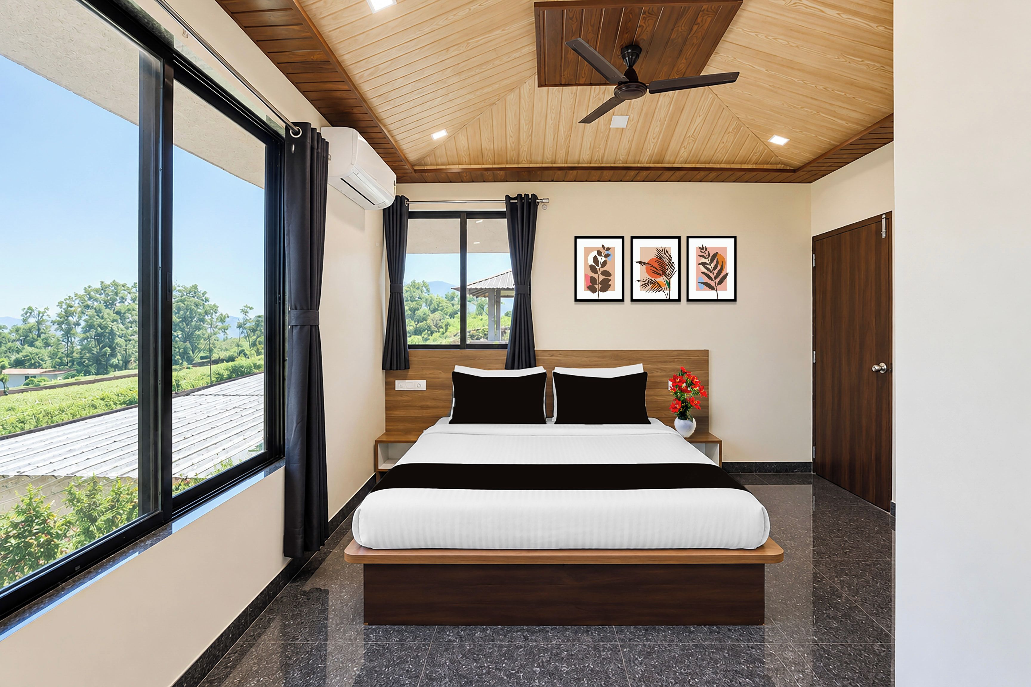 A modern bedroom with a large bed, a ceiling fan, and a view of a green landscape through the window.