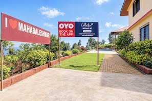 Uma trilha leva a um edifício com uma placa indicando serviço de reservas para um local chamado Mahabaleshwar.
