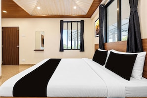 A hotel room with a large bed, a wooden ceiling, a window with curtains, a mirror, and a picture on the wall. - Collection O Parsi Point Mahabaleshwar (Mahabaleshwar)
