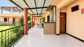 Un pasillo limpio y moderno con una recepción, un letrero que indica un comedor y un espacio exterior verde visible a través de la barandilla.