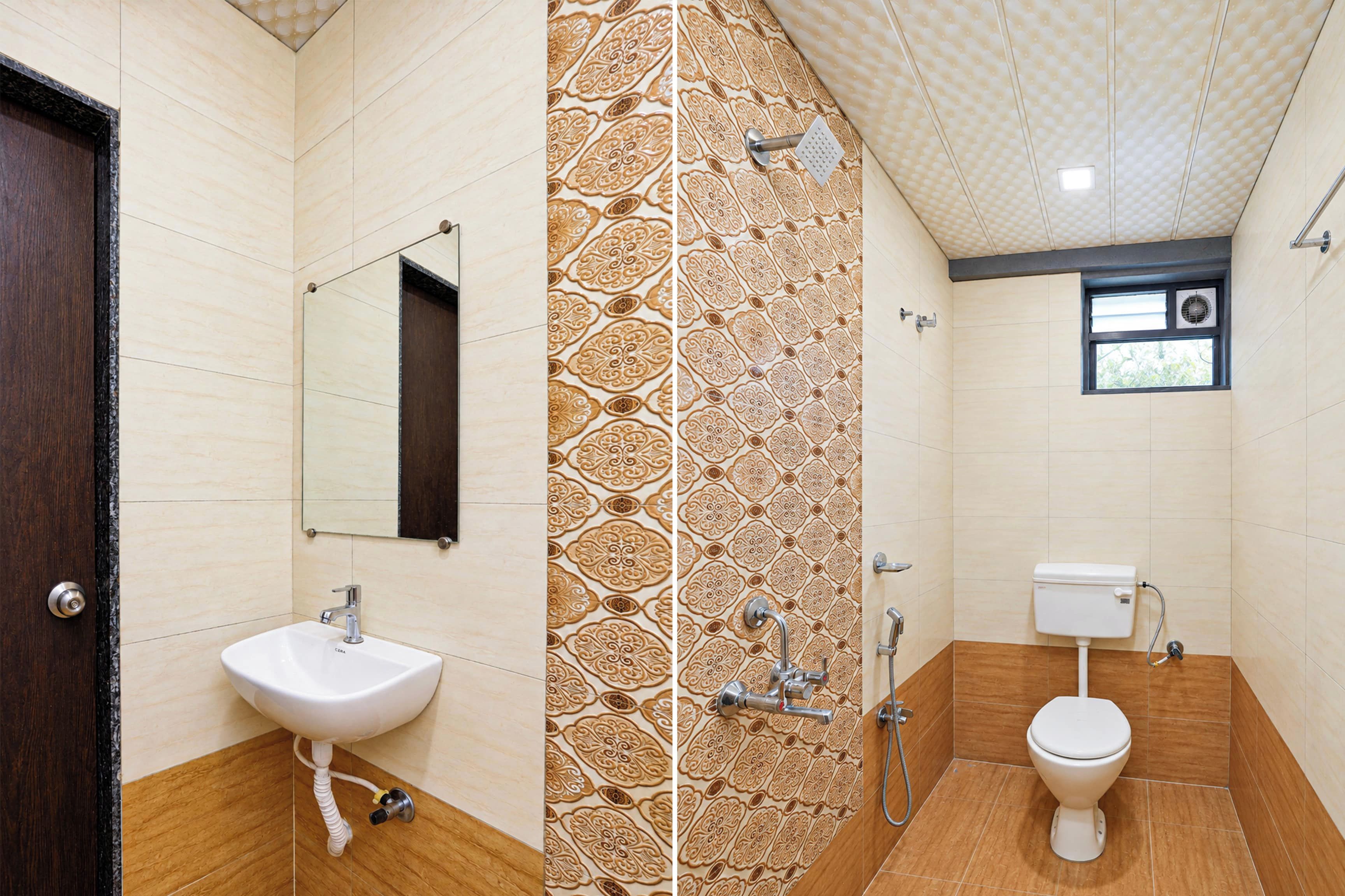 A bathroom with a sink, mirror, patterned wall, shower, and toilet.