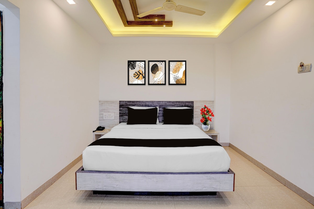 Un dormitorio moderno con cama, mesitas de noche, ventilador de techo y cuadros en la pared.