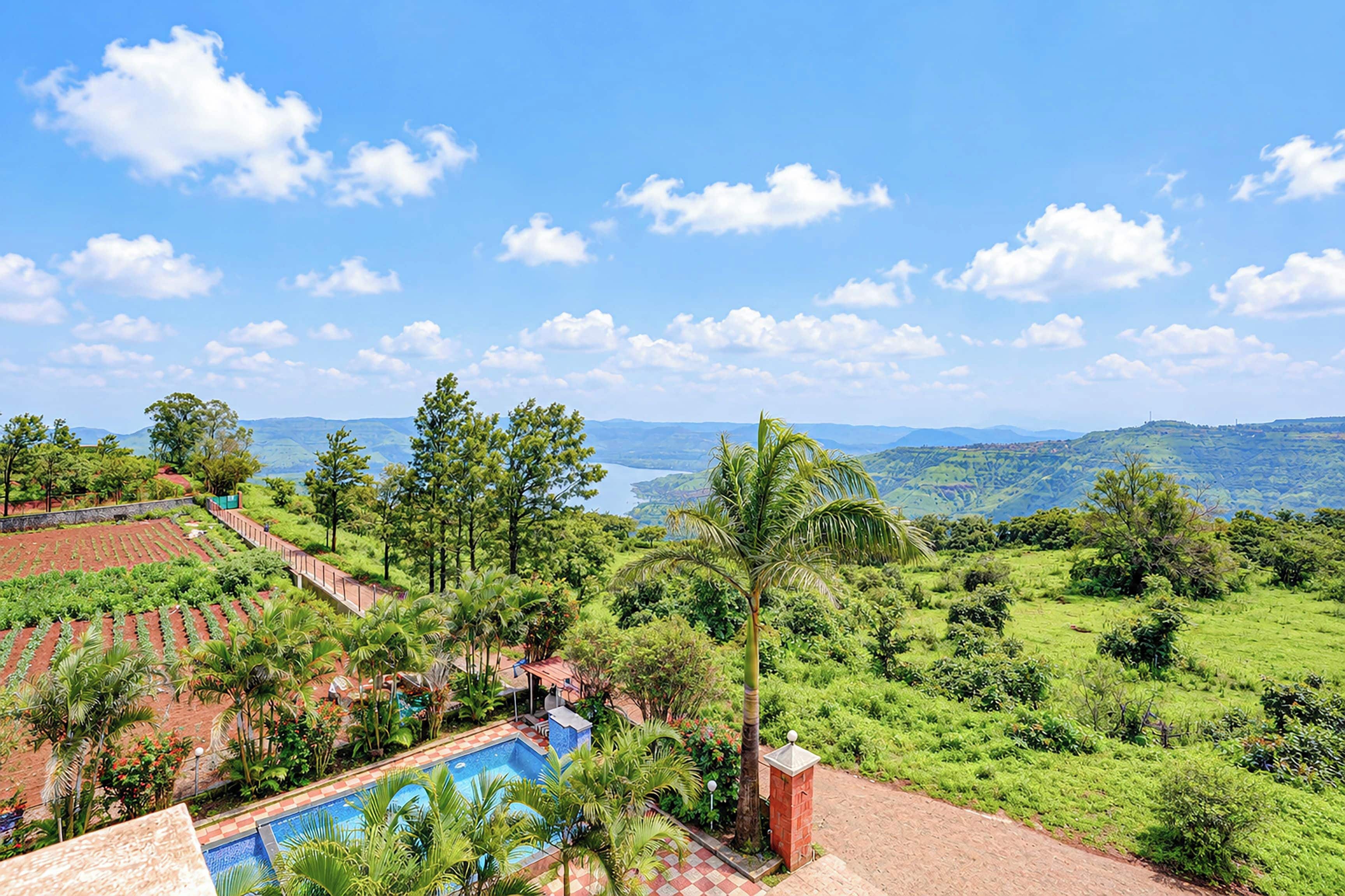 Una piscina rodeada de vegetación exuberante y vistas a colinas distantes.
