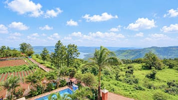 Una piscina rodeada de vegetación exuberante y vistas a colinas distantes.