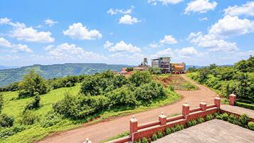 Un paisaje montañoso con un camino pavimentado que conduce a un edificio de varios pisos y techo plano.