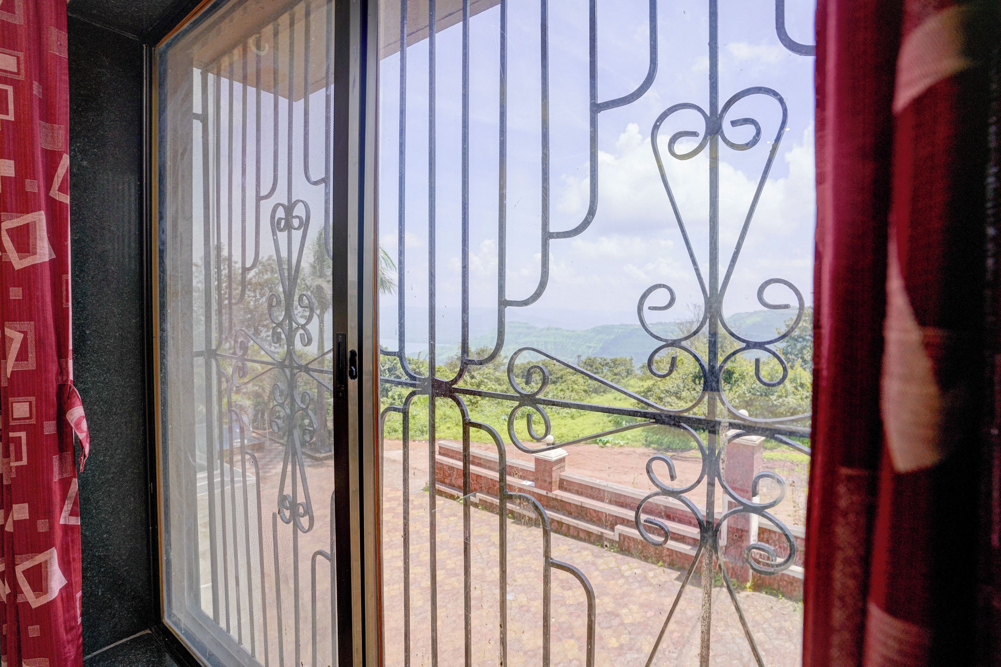 A window with metal bars and a view of a green landscape.
