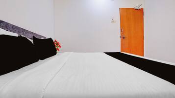 Una habitación de hotel con una cama, una puerta de madera y una lámpara fijada a la pared.