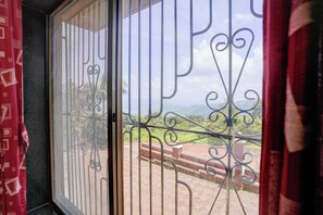 Una ventana con barrotes y vista a un paisaje verde.