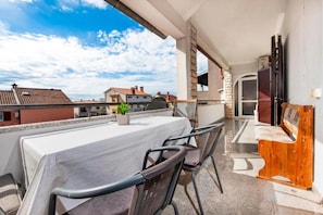 Un balcon avec une table et des chaises, un banc en bois et une vue sur les bâtiments voisins.